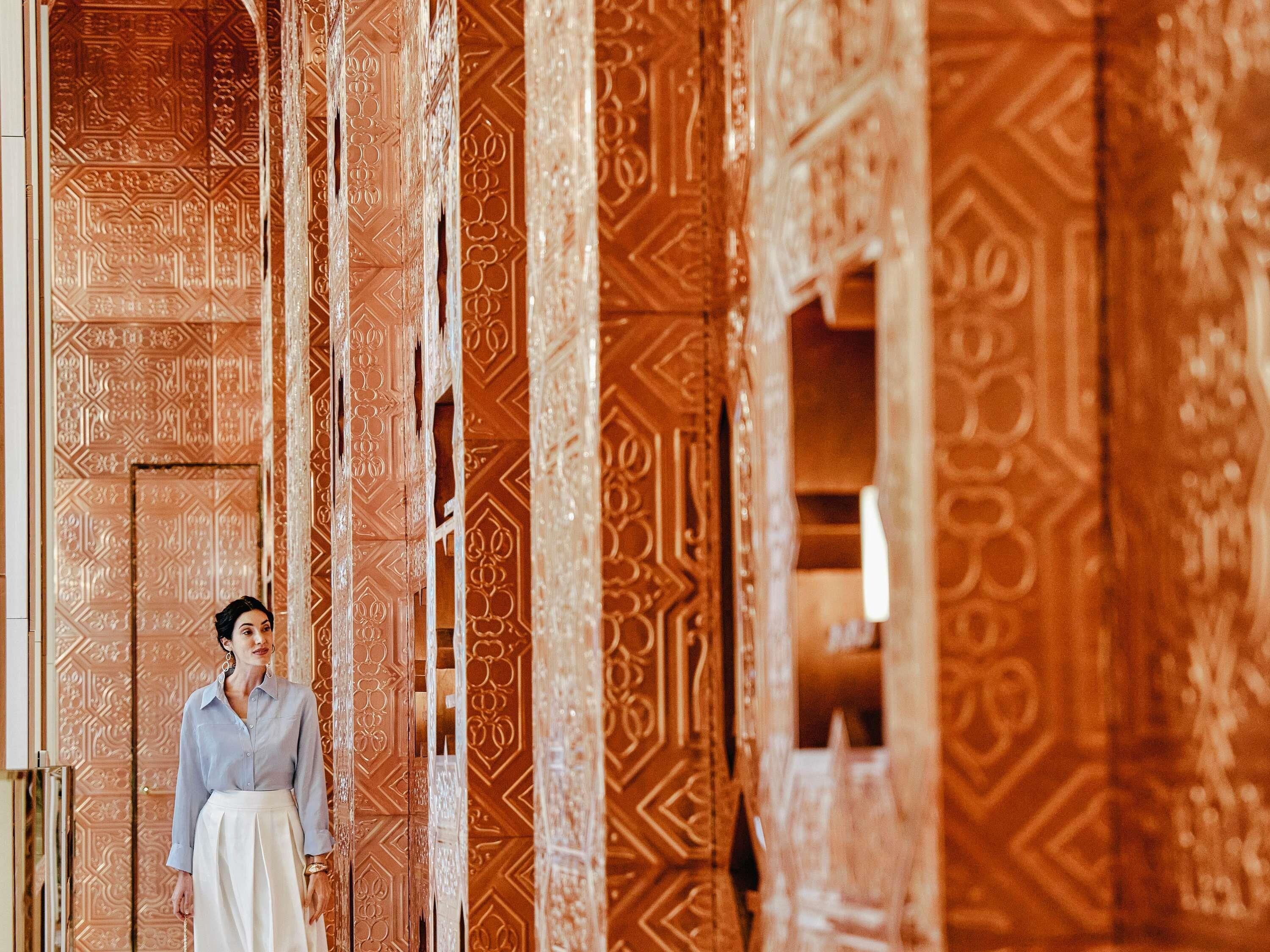 A person standing in a room with intricate geometric patterns on the walls.