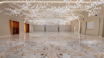 A spacious hall with a polished marble floor and a ceiling adorned with numerous hanging light fixtures.