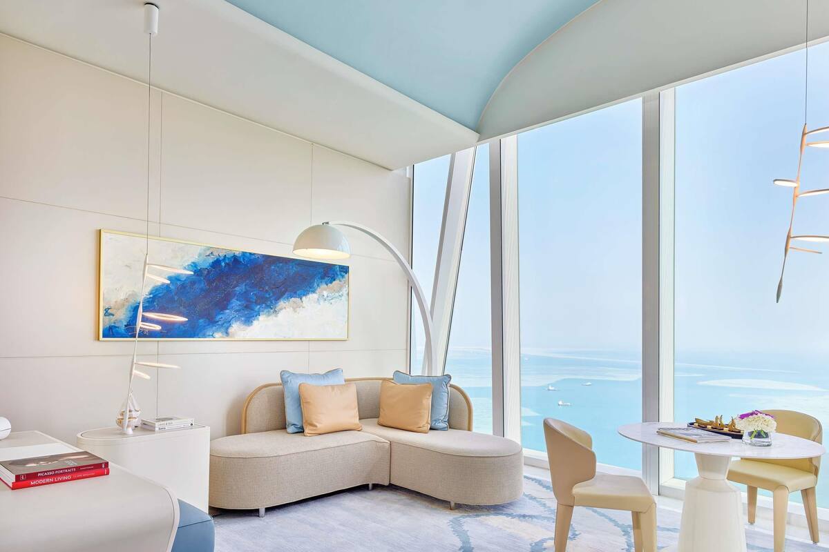 Uma sala de estar moderna com uma janela grande, um sofá, uma mesa e um quadro.