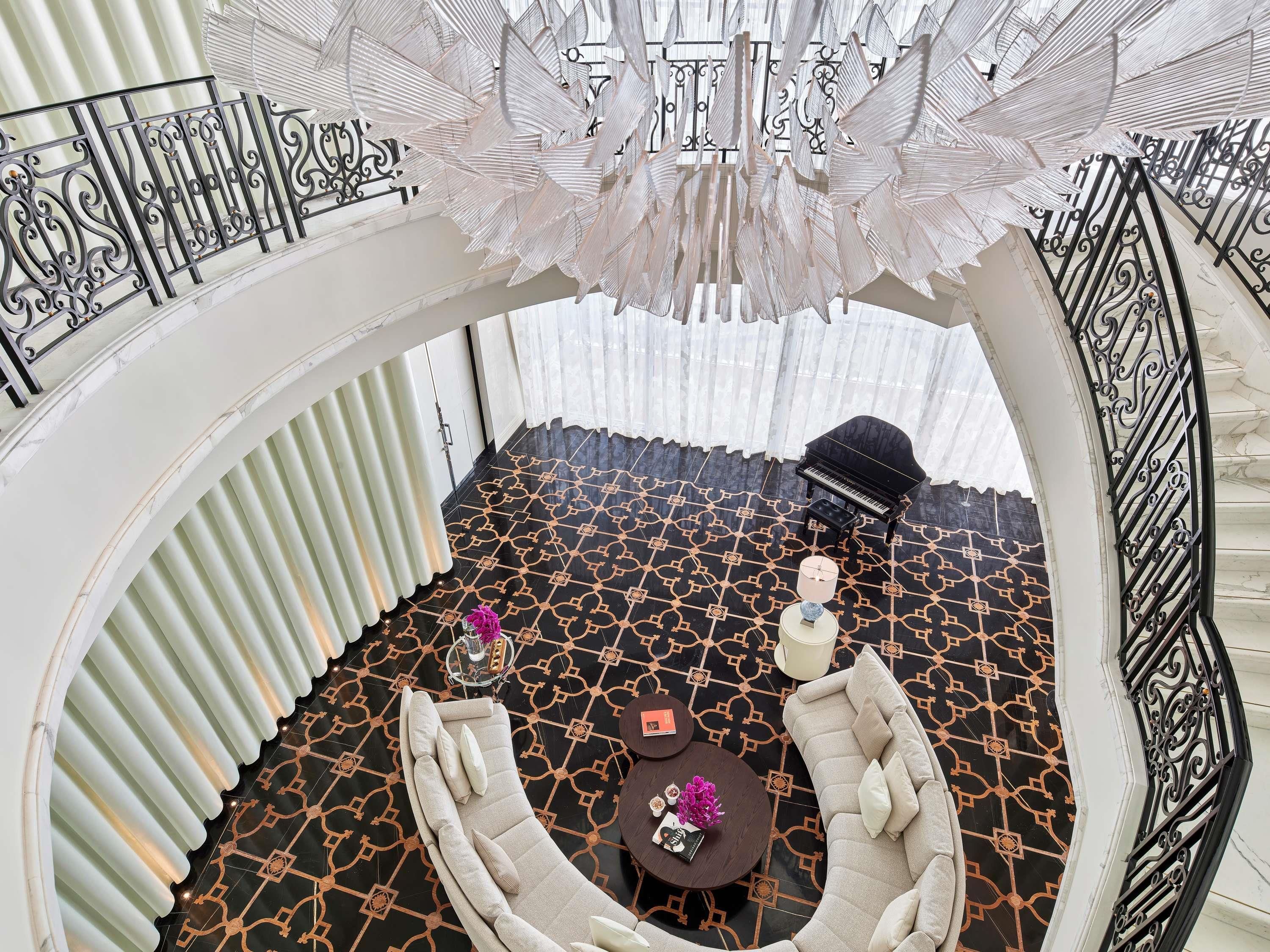 A grand room with a piano, a sofa, and a patterned floor.