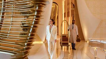 A modern interior with a curved reflective floor, a brass elevator, and a patterned wall.