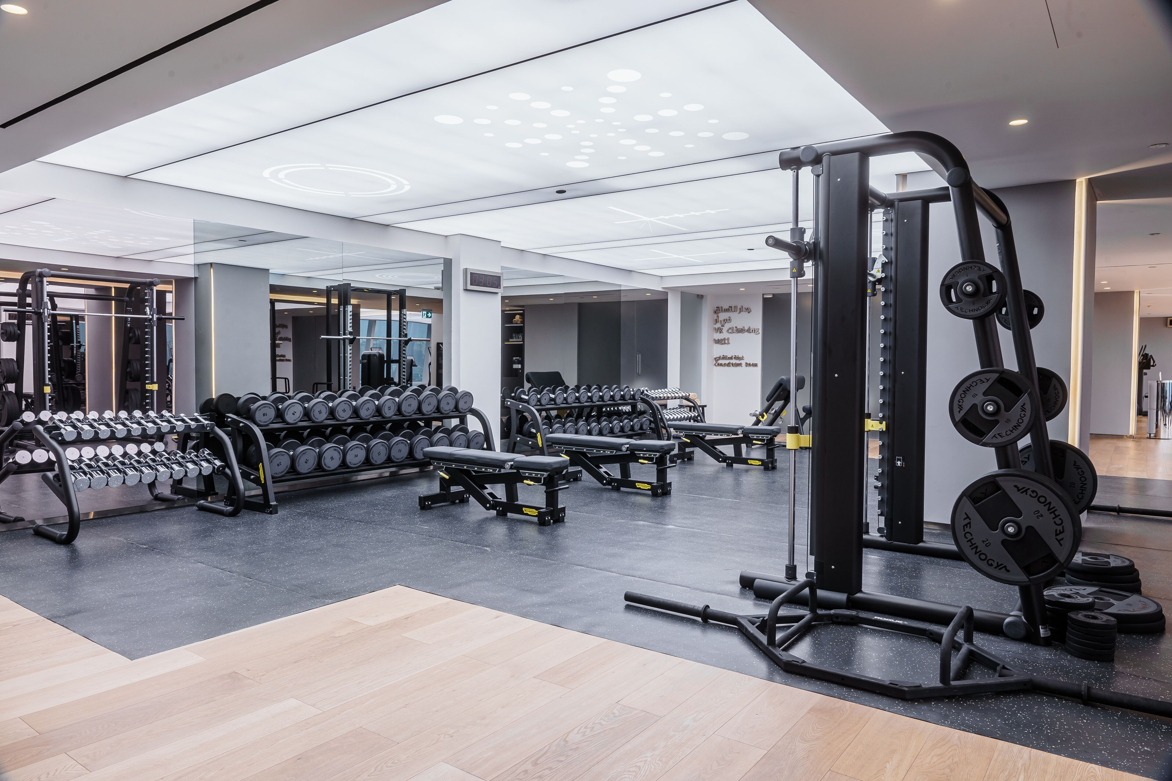 A modern gym with weightlifting equipment, benches, and dumbbells.