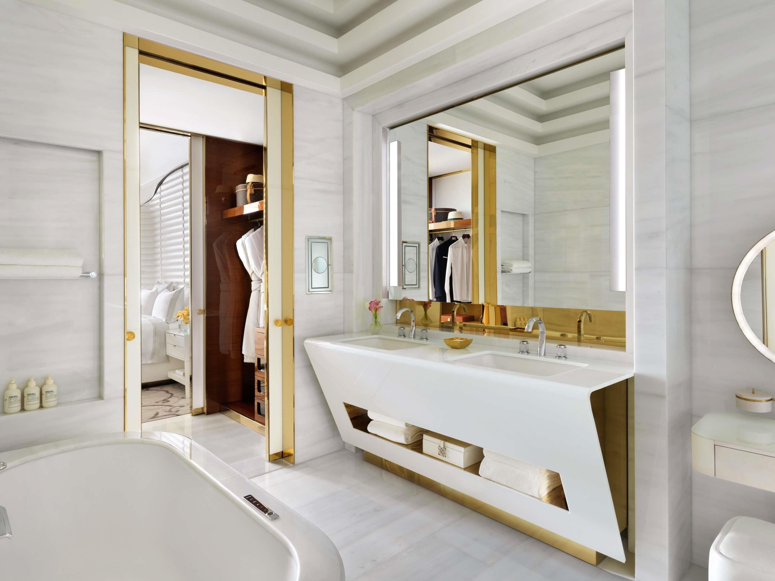 A modern bathroom with a large vanity, a bathtub, and a walk-in closet.