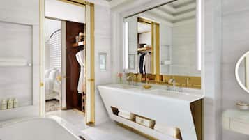 A modern bathroom with a large vanity, a bathtub, and a walk-in closet.