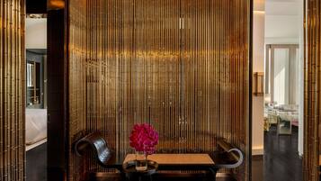 A reception area with a black sofa, a small table with a vase of flowers, and a bamboo wall.