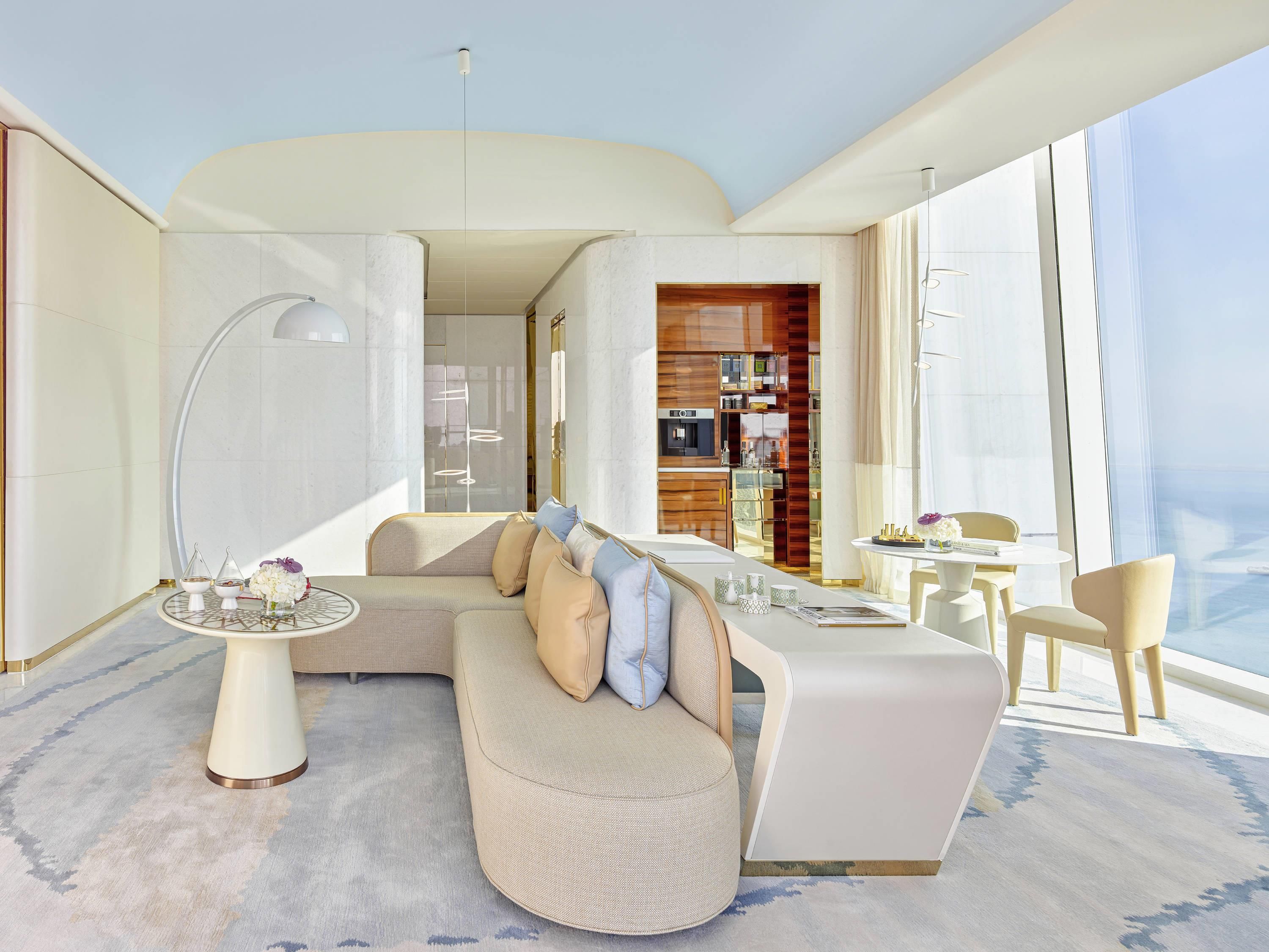 A modern living room with a sofa, a dining table, and a kitchen area.