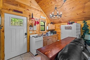 Ein Ferienhaus-Innenraum mit Holzausstattung, einer Küche mit Herd und Spüle, einem Esstisch und einem Weihnachtsbaum.