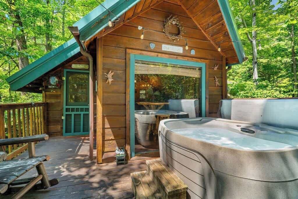 Eine Holzhütte mit Whirlpool, Sitzgelegenheit im Freien und einer Terrasse.