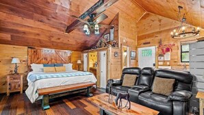 Ein Holzkaminzimmer mit einem Bett, einer Couch und einem Esstisch.