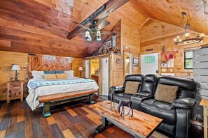 Ein Holzkaminzimmer mit einem Bett, einer Couch und einem Esstisch.