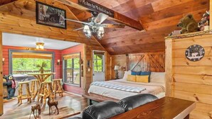 Ein gemütliches Blockhaus-Interieur mit einem Bett, einem Esstisch und einem Deckenventilator.