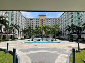 Un patio de hotel con piscina, palmeras y vistas del exterior del edificio.