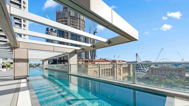 A rooftop pool with clear blue water, modern architecture, and a view of the city skyline.
