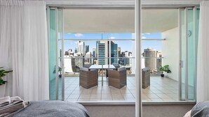 A hotel room with a city view, a balcony with a table and chairs, and a sliding glass door.
