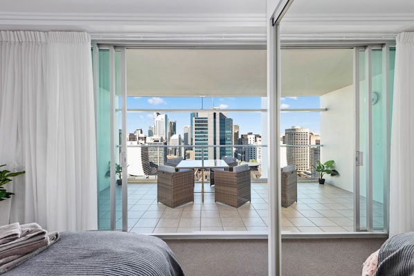 Enjoy a city view from the balcony with a dining set and potted plant.
