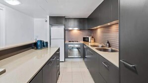 A modern kitchen with grey cabinets, a stainless steel sink, and a microwave.