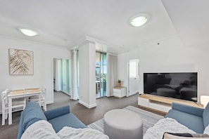 Relax in this stylish living room with a large flat-screen TV, comfortable seating area, and dining table.