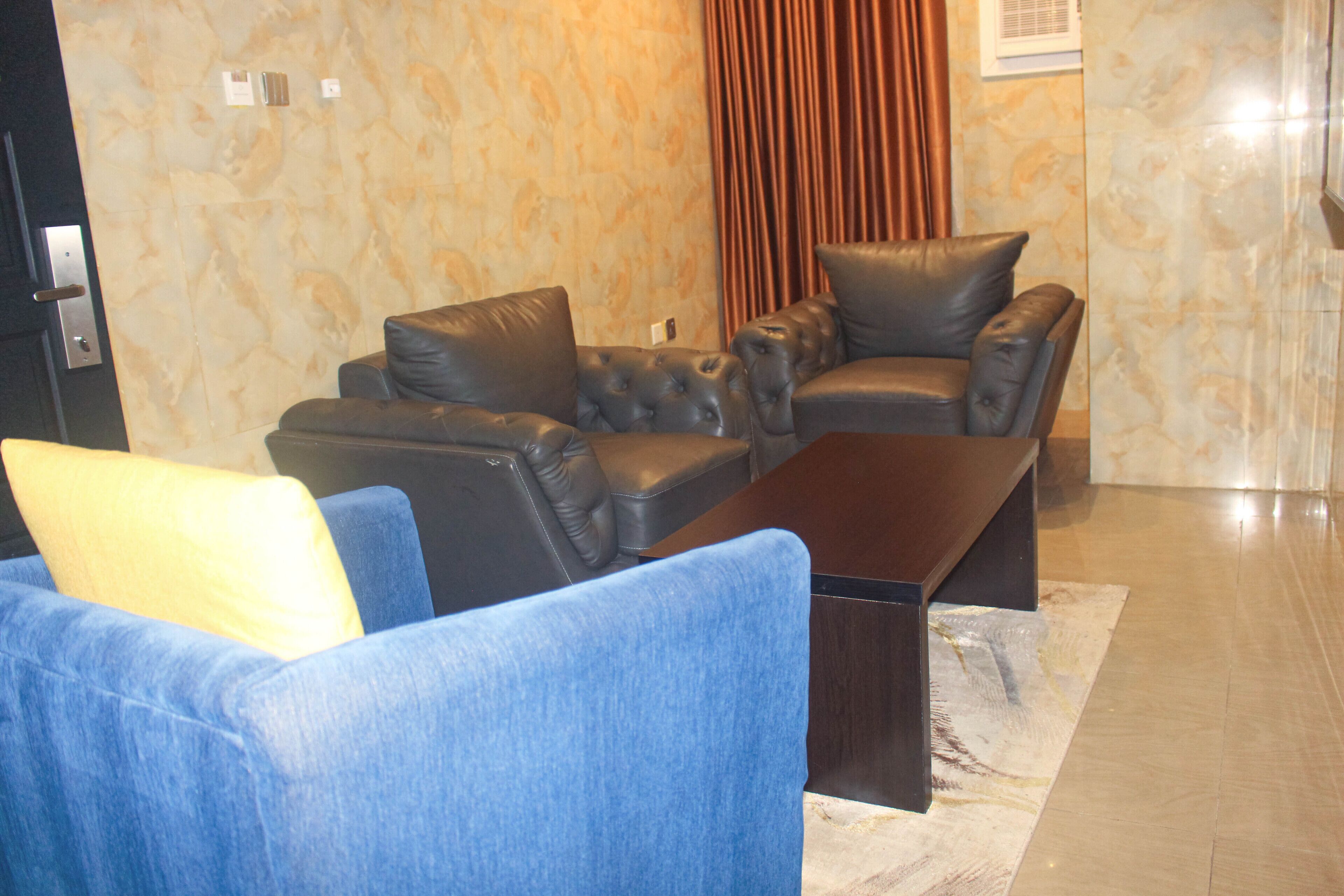 A modern living room with a sectional sofa, a blue armchair, and a dark coffee table.