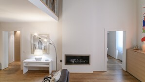 Ein modernes Interieur mit einem weißen Konsolentisch, einer Stehlampe, einem Kamin und einer Treppe, die in ein Obergeschoss führt.