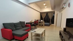 A modern living room with a red and grey sectional sofa, a wooden coffee table, and a TV stand. - Pavilion Bukit Jalil @ REVO Cozy Studio Suite (Kuala Lumpur)