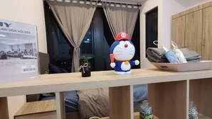 A reception desk with a large poster, a plush toy, and a shelf with various items. - Pavilion Bukit Jalil @ REVO Cozy Studio Suite (Kuala Lumpur)