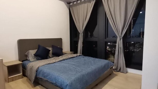 A bedroom with a bed, nightstand, and large window with curtains. - Pavilion Bukit Jalil @ REVO Cozy Studio Suite (Kuala Lumpur)