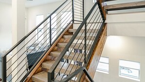 A multi-level interior with a staircase featuring wooden steps and metal railings. - EaDo Signature - East of Downtown Spacious Home (Houston)