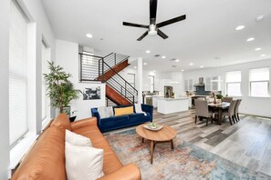 A spacious living area with a sofa, coffee table, and a staircase leading to a kitchen. - EaDo Signature - East of Downtown Spacious Home (Houston)