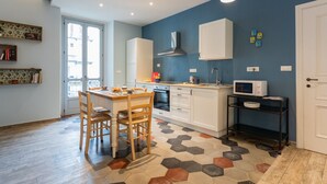 Une cuisine moderne avec des meubles blancs, un four à micro-ondes et un coin repas comprenant deux chaises en bois.