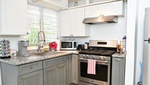 A kitchen with grey cabinets, a stainless steel stove, a microwave, and a sink.