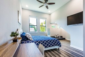 Ein Schlafzimmer mit Bett, Deckenventilator, Fernseher und Fenster.