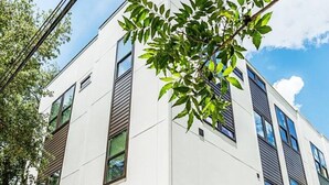 Un edificio moderno de dos pisos con techo plano, ventanas amplias y un garaje.