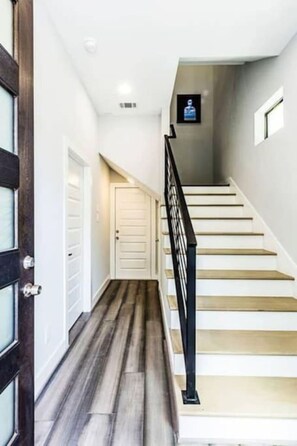 A staircase with a black railing, a wooden floor, and a white door at the top.
