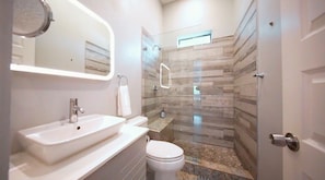 A modern bathroom with a sink, toilet, and shower area. - Montrose Stay: 7 Rooms, 7 Baths & Rooftop Lounge (Houston)