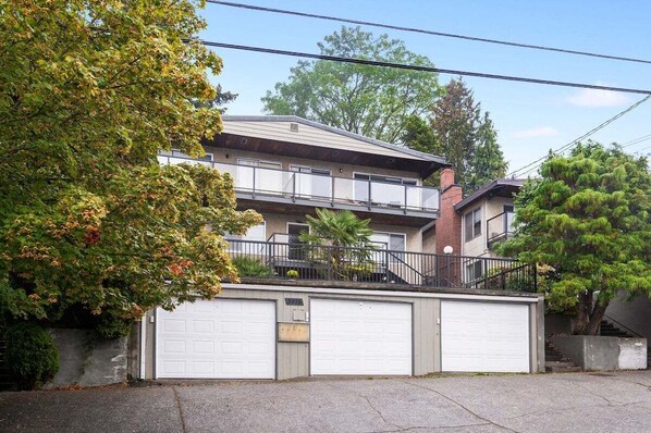A two-story residential building with a balcony, a garage, and a staircase leading to the upper floor.
