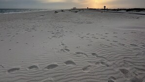 Ein Strand mit Fußabdrücken und einer Stra ße in der Ferne.