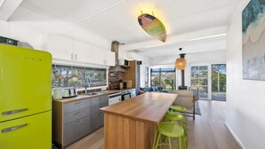 Una cocina moderna con una isla de madera, electrodomésticos de acero inoxidable y un refrigerador verde brillante.