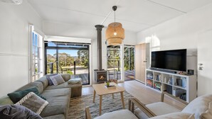 Una sala de estar moderna con un sofá modular, un televisor, una estantería y una chimenea.