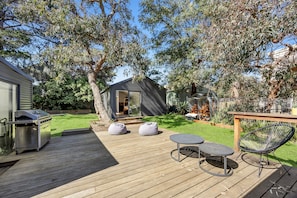 A deck with outdoor seating, a barbecue grill, and a small shed.
