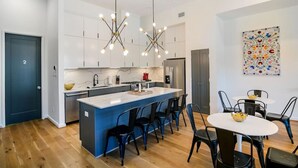 Una cocina moderna con armarios blancos, una isla azul y sillas negras.