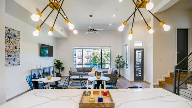Una sala de estar moderna con comedor, ventilador de techo y escalera.