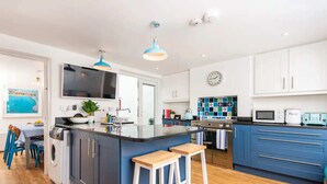 Una cucina moderna con isola centrale, mobili blu e televisore a schermo piatto.