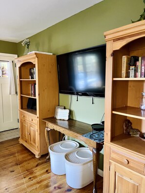 Cozy living space with a flat-screen TV, wooden cabinet, and small table.