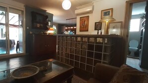 Un salon avec une table basse en verre, un canapé, un téléviseur et un coin cuisine visible à travers une porte coulissante.