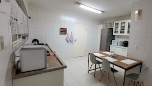 Eine Küche mit Kühlschrank, Mikrowelle und einem Esstisch mit Stühlen.