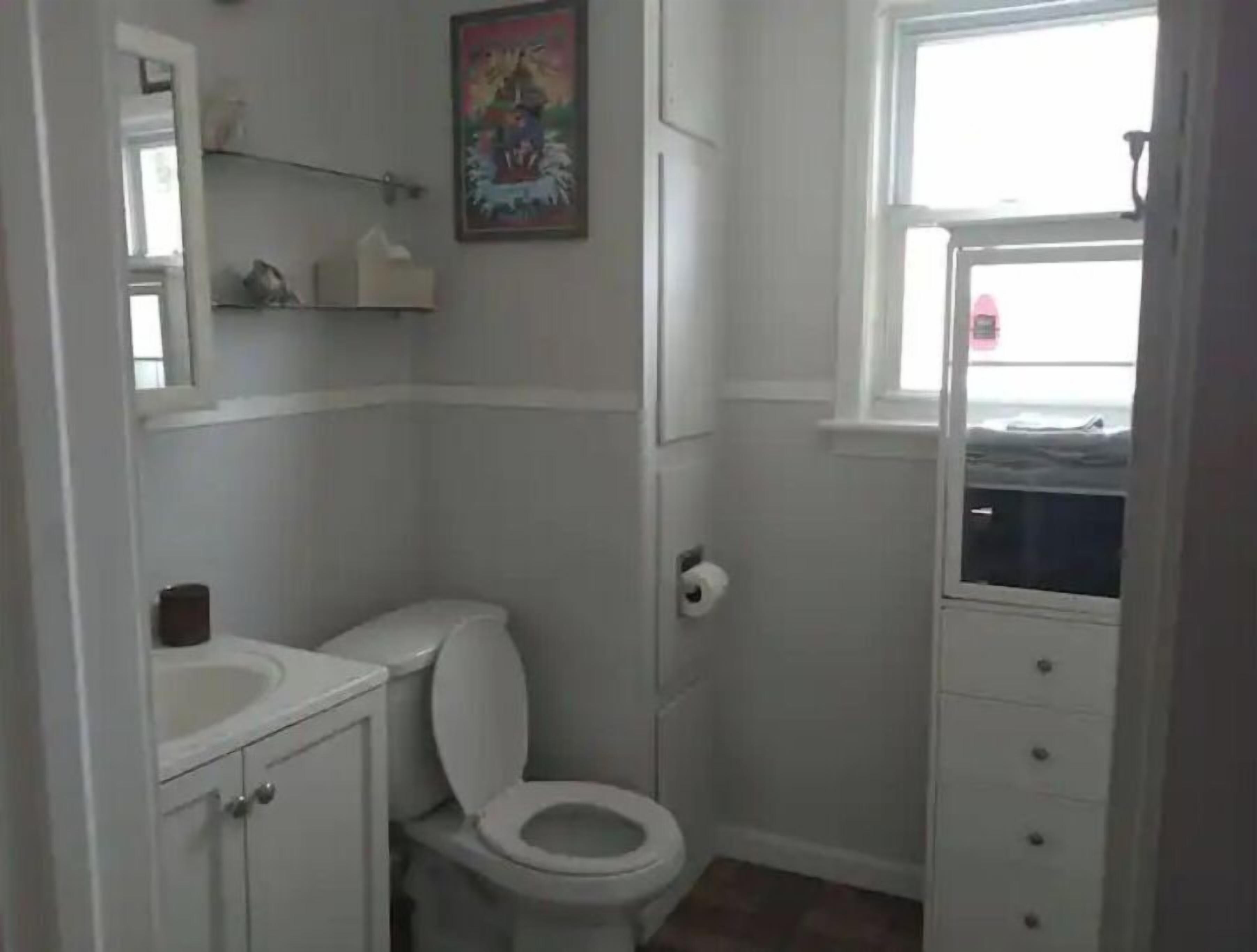 A small, white bathroom with a toilet, a sink, and a window.