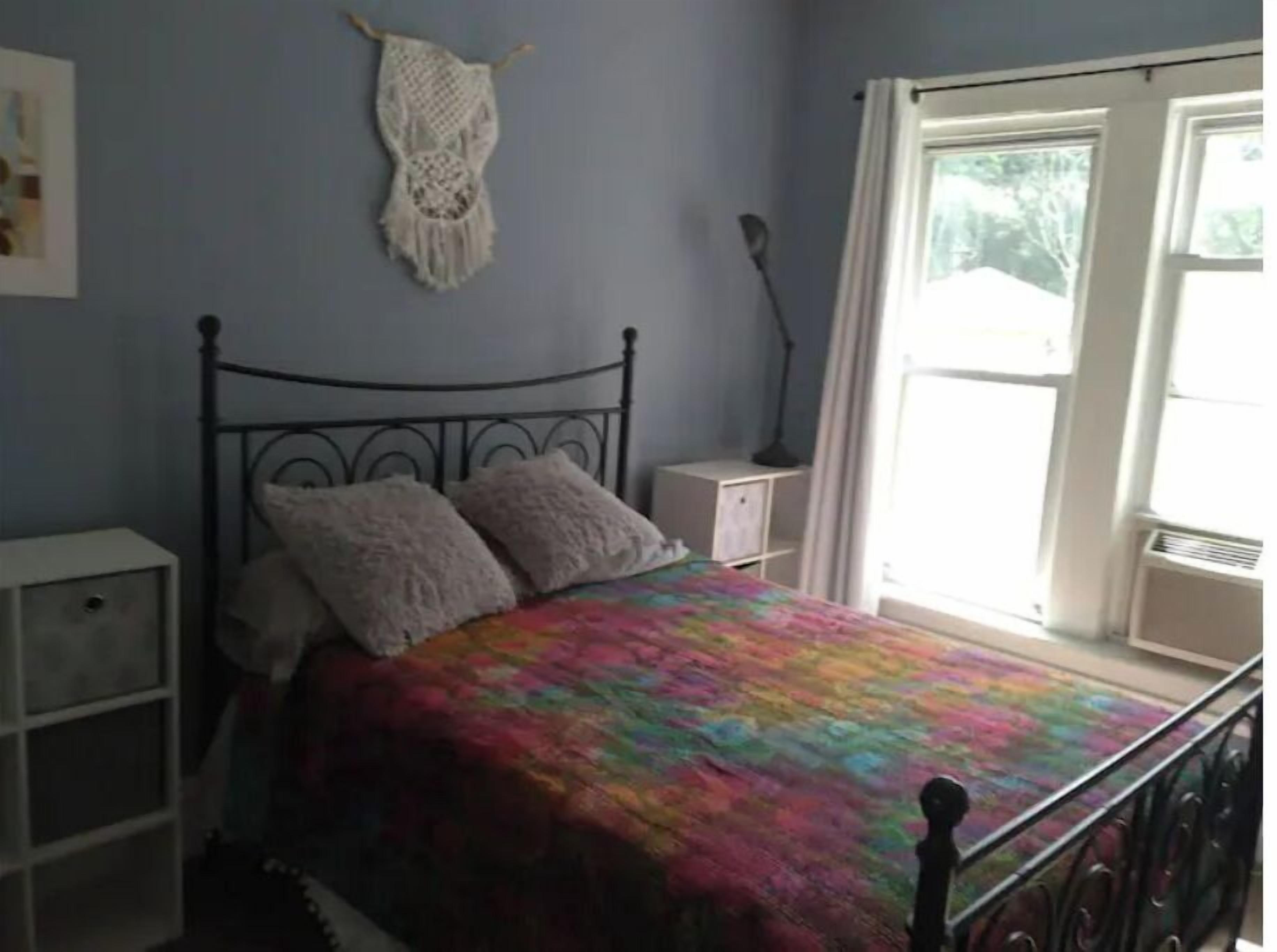 A bedroom with a bed, a nightstand, a lamp, and a window with curtains.