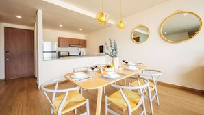 A modern dining area with a wooden table set for six, white chairs with woven seats, and two pendant lights.
