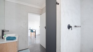 A modern bathroom with a white sink, dark door, and a visible towel. - HoneyBee Cottage (Yzerfontein)