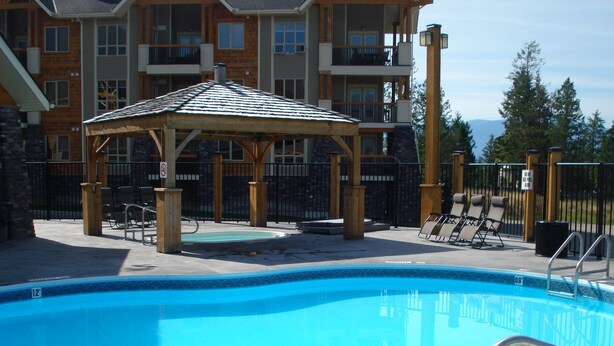 A swimming pool with lounge chairs and a gazebo.